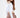Back view of a white Adriana off-shoulder long sleeve crop top paired with brown high-waisted trousers.
