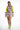 Model in Alexia mauve and neon yellow cropped windbreaker top and matching athletic shorts with white sneakers.