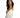 Rear view of a woman wearing the Evie Sleeveless Bodysuit in Carbon black with white high-waisted trousers.