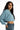 Light blue long sleeve Stevie ribbed crop top with raw hem worn by model in denim jeans against a white background.