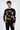 Man wearing Untimely long-sleeve black shirt with colorful pixel art graphics, including a mushroom and emoji face.