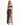A model poses in a dark two-piece outfit featuring a knotted top and a high-slit skirt with a floral pattern.