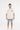 A man wearing a beige oversized t-shirt with graphic prints, paired with denim shorts and white sneakers.
