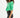 Side view of a woman in the cropped green Ride Blazer with ruched sleeves and high-waisted black trousers.