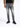 A person stands wearing distressed gray jeans and black sneakers, showcasing a casual, modern style.