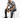 A man sits on a white cube, wearing a black and white patterned short-sleeve shirt with distressed jeans and black sn...