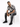 A man sits on a white cube, wearing a black and white patterned short-sleeve shirt with distressed jeans and black sn...