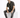 A man sits on a white cube, wearing a short-sleeve striped shirt with dark and light tones, paired with distressed je...