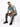 A man sits on a white cube, wearing a short-sleeve, tie-dye shirt with shades of teal and gray, paired with distresse...