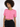 A model wearing a cropped pink top with short sleeves and two front pockets, paired with black pants.