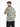 A man wearing a short-sleeve, patterned shirt with green and beige colors, posing from the back.