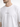 A close-up of a man wearing a white oversized t-shirt featuring a minimalist text design on the front.