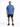 A man stands confidently in a blue oversized t-shirt paired with black shorts and sneakers.