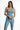 Model wearing light blue Karina Crop Tank, a one-shoulder sleeveless top with asymmetrical neck on white background.