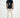 Rear view of model wearing MAC cream streetwear joggers with elastic cuffs and a black graphic t-shirt.