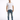 A man stands confidently in a fitted white t-shirt, distressed blue jeans, and white sneakers.