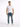 A man stands confidently in a fitted white t-shirt, distressed blue jeans, and white sneakers.