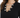 Close-up of a black top featuring a V-neckline adorned with decorative silver embellishments and rhinestones.