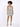A model poses in a shimmering silver dress with a cutout design and strappy heels, showcasing a stylish look.