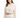 A woman models a cropped, cream-colored hoodie with a drawstring and relaxed fit, paired with matching pants.