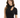 A woman with long, wavy hair wears a fitted black top featuring a mock neck and a stylish cutout.