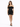 A model poses in a fitted black off-the-shoulder dress with a ruched design and strappy heels.