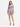 A model poses in a colorful floral dress with long sleeves and a cinched waist, paired with strappy heels.