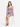 A model sits on a stool wearing a colorful floral dress with long sleeves and a cinched waist.