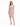 A woman stands in a relaxed-fit, short-sleeve pink dress paired with black strappy heels against a white background.