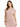 A woman with wavy hair wears a soft pink, short-sleeved dress, showcasing a relaxed fit and minimalistic design.