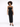 A model poses in a black, sparkly dress with cut-out details and thin straps, showcasing a stylish silhouette.