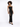 A model poses in a black, glittery dress featuring cut-out details along the sides, paired with black heels.