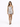 A model poses in a silver, form-fitting dress with a ruched design and thin straps, paired with black heels.