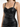Close-up of a woman wearing a fitted black leather dress with thin straps and structured bodice details.