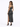 A woman in a sparkling black two-piece outfit with a high slit, paired with black heels, poses from the back.
