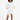 A model poses in a white hooded garment with unique side cutouts and metal ring accents, showcasing a modern style.