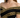 Close-up of a woman wearing an off-shoulder black top with intricate gold embroidery detailing.