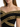 Close-up of a woman wearing an off-shoulder black top with intricate gold embroidery detailing.