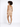 A model with curly hair poses in a fitted, sleeveless beige dress, showcasing a casual look with white sneakers.