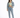 A woman stands confidently in a cropped green top, denim jacket, and light blue jeans, paired with white sneakers.