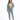 A woman stands confidently in a cropped green top, denim jacket, and light blue jeans, paired with white sneakers.