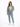 A woman stands confidently in a cropped green top, denim jacket, and light blue jeans, paired with white sneakers.