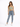 A woman stands confidently in a light green crop top and high-waisted blue jeans, paired with white sneakers.