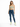 A woman stands confidently in a light green crop top and distressed blue skinny jeans, paired with white sneakers.