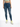A woman wearing a cropped green top and distressed blue skinny jeans, paired with white sneakers featuring neon accents.
