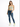 A woman stands confidently in a light green cropped top, distressed blue jeans, and white sneakers with green accents.