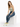 A woman sits on a white cube, wearing a light green tank top, distressed blue jeans, and white sneakers with neon acc...