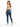 A woman with long hair wears a light green crop top and fitted blue jeans, paired with white sneakers.