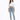 A woman stands confidently in a cropped white long-sleeve shirt and light blue jeans, paired with gray slippers.