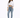 A woman stands confidently in a cropped white long-sleeve top, light blue jeans, and gray fuzzy slippers.